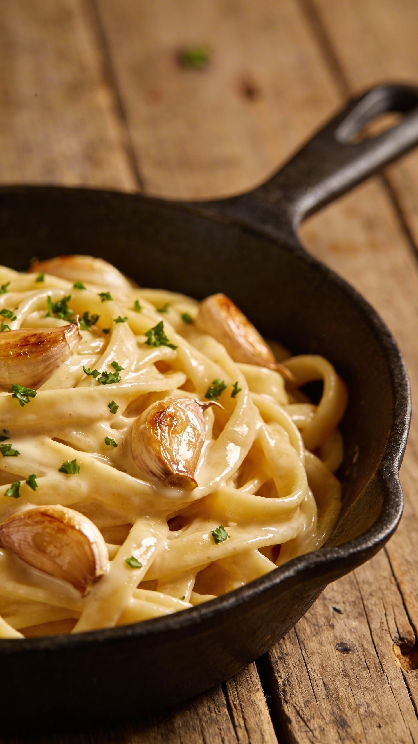 [HERO] closeup creamy garlic pasta in skillet on rustic wood