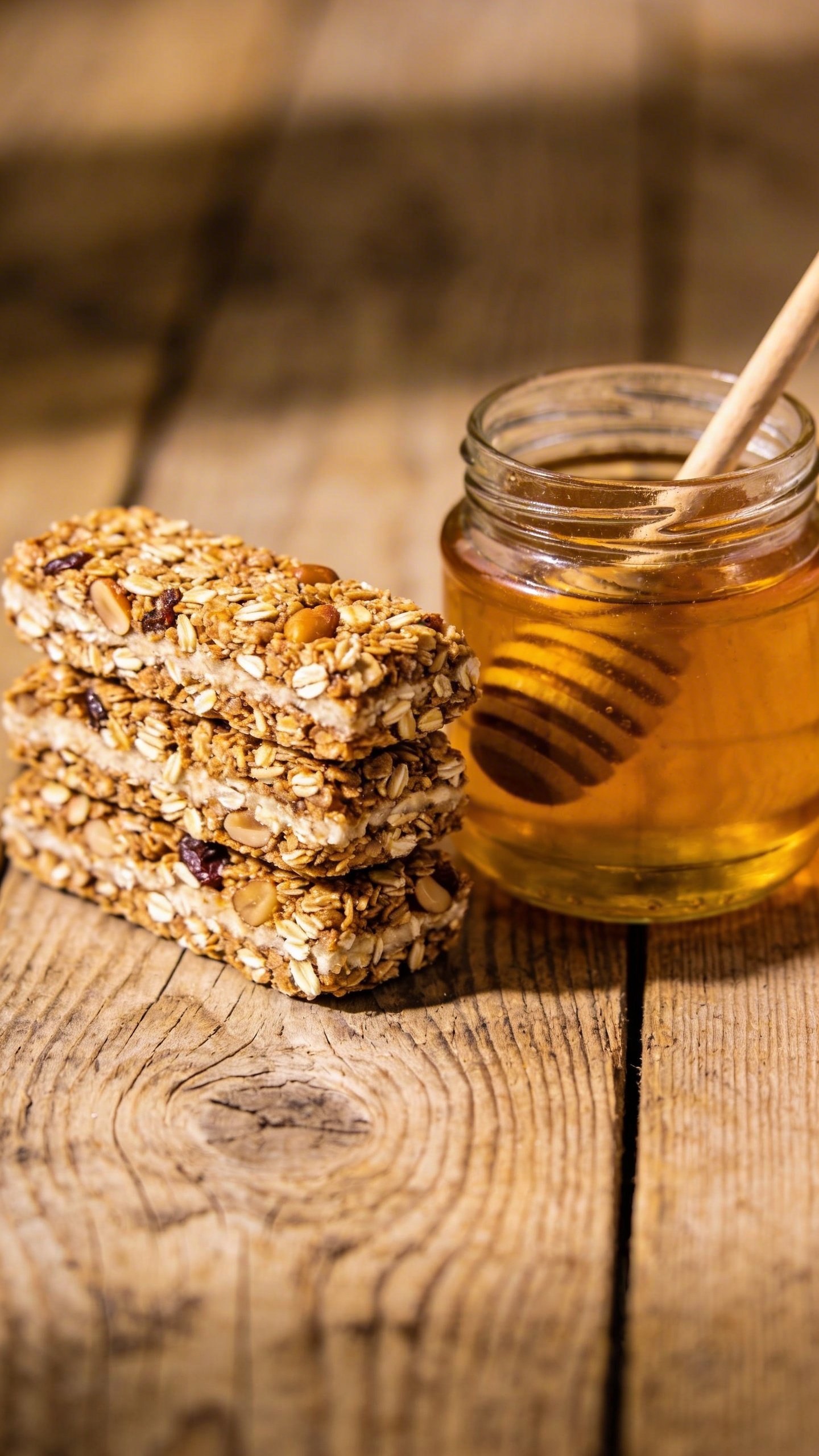 [CLOSING] stacked granola bars beside a jar of honey on wood