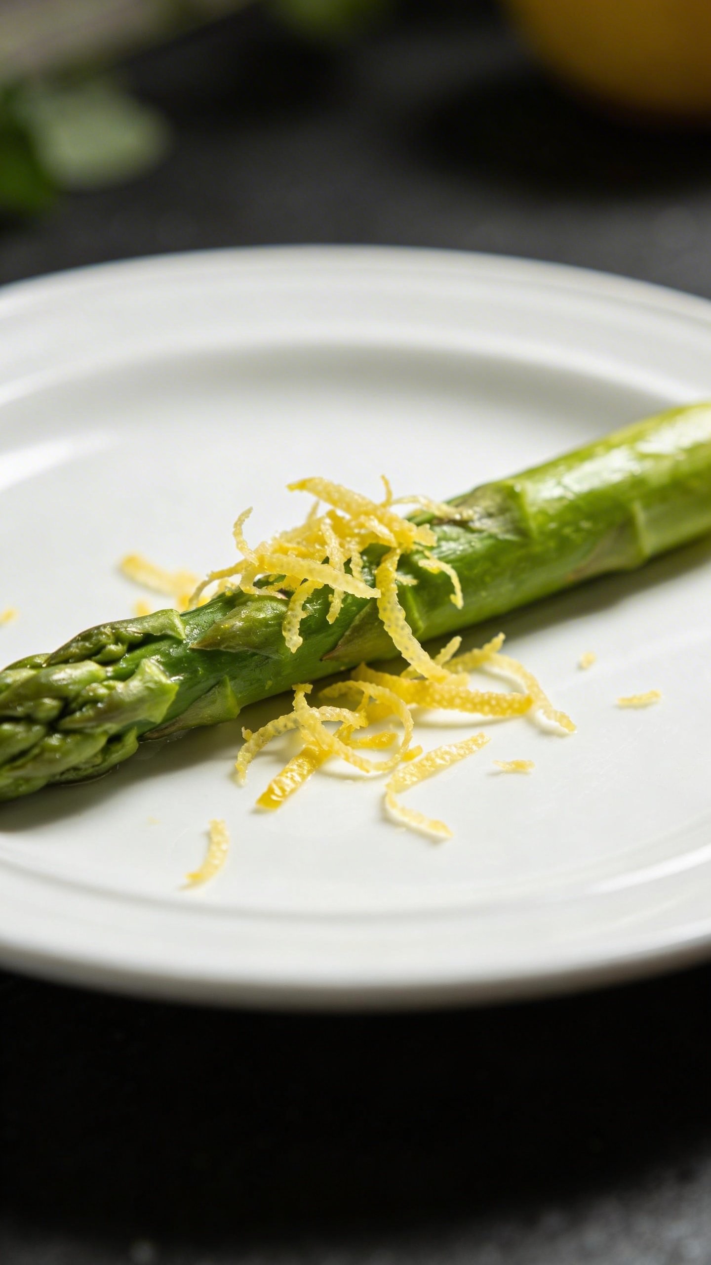 [RECIPE 1] single asparagus spear with lemon zest on white plate